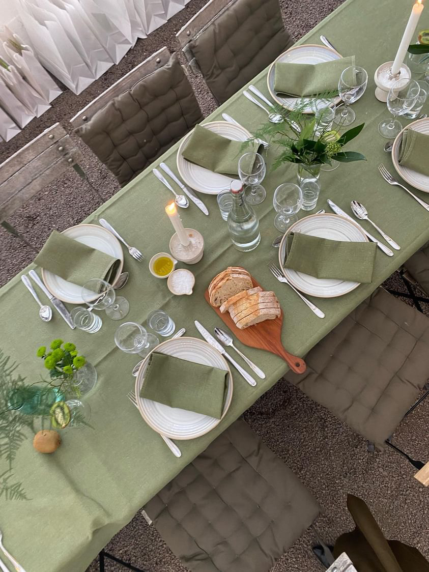 En grön dukning från ett event. Grön duk, gröna servetter, gröna blommor.